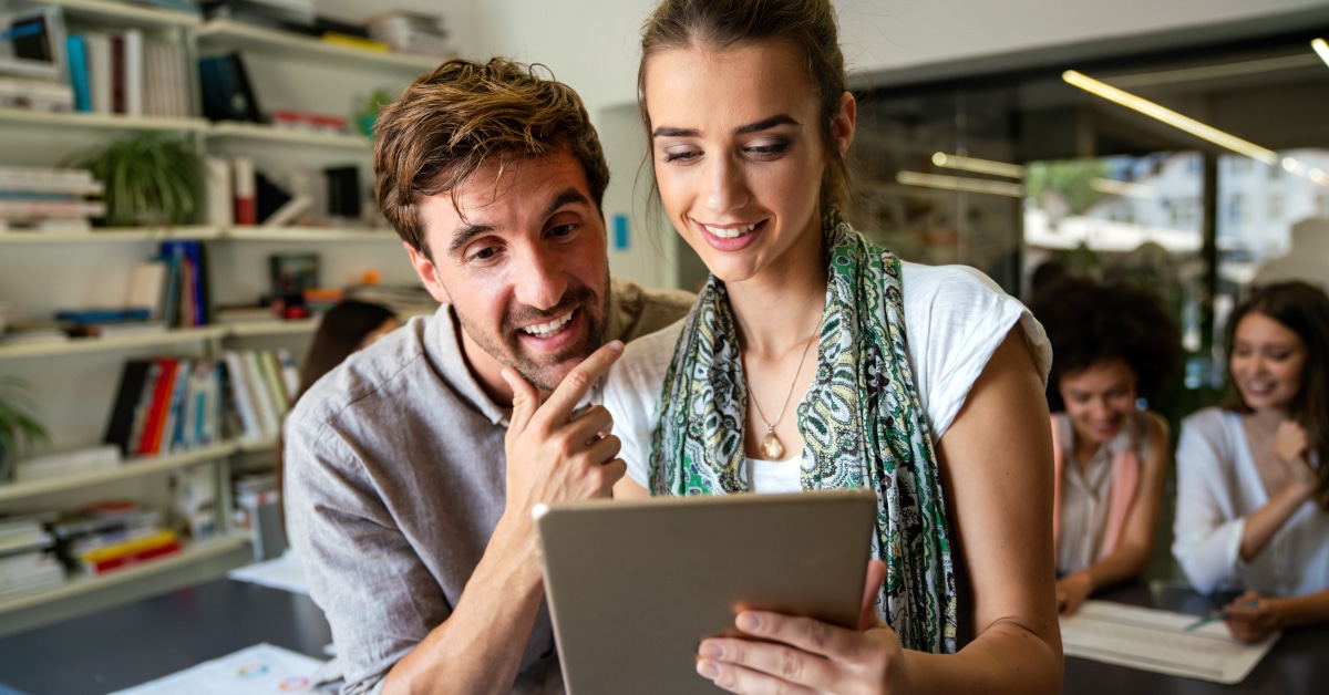 A man and woman are looking at a tablet at work
