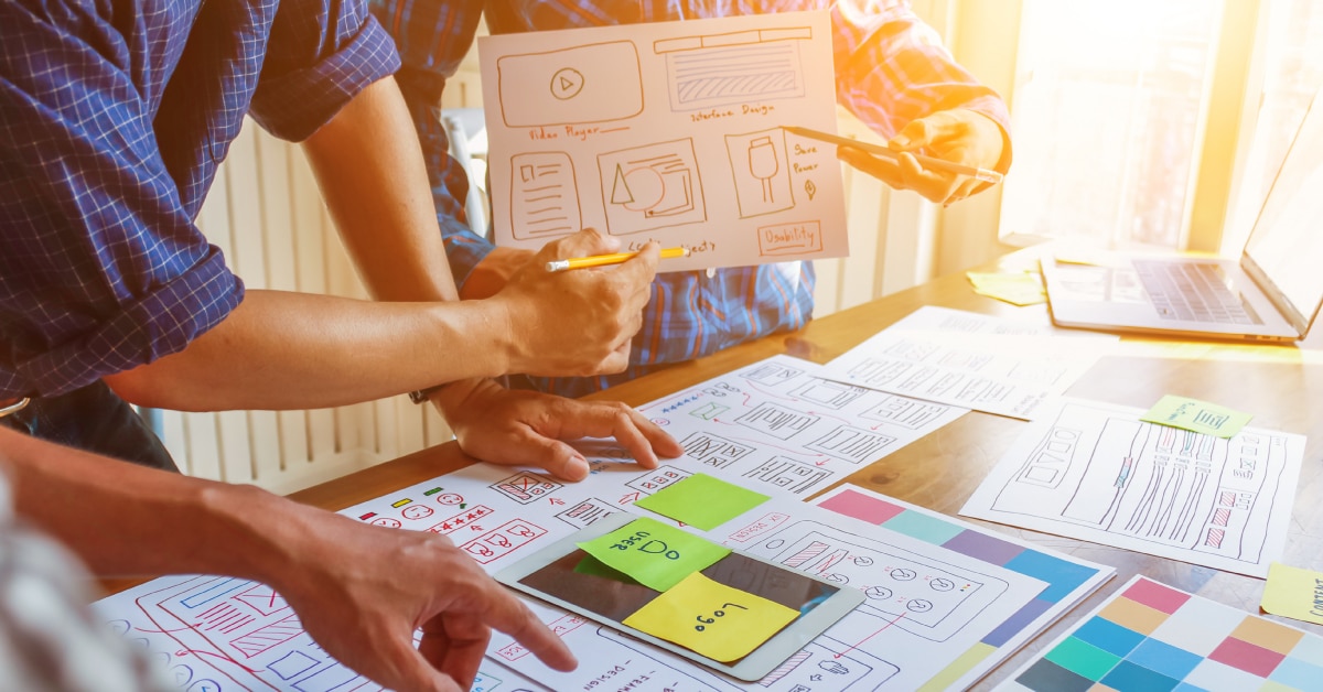 Image of three people gathered around a desk with papers and graphics.