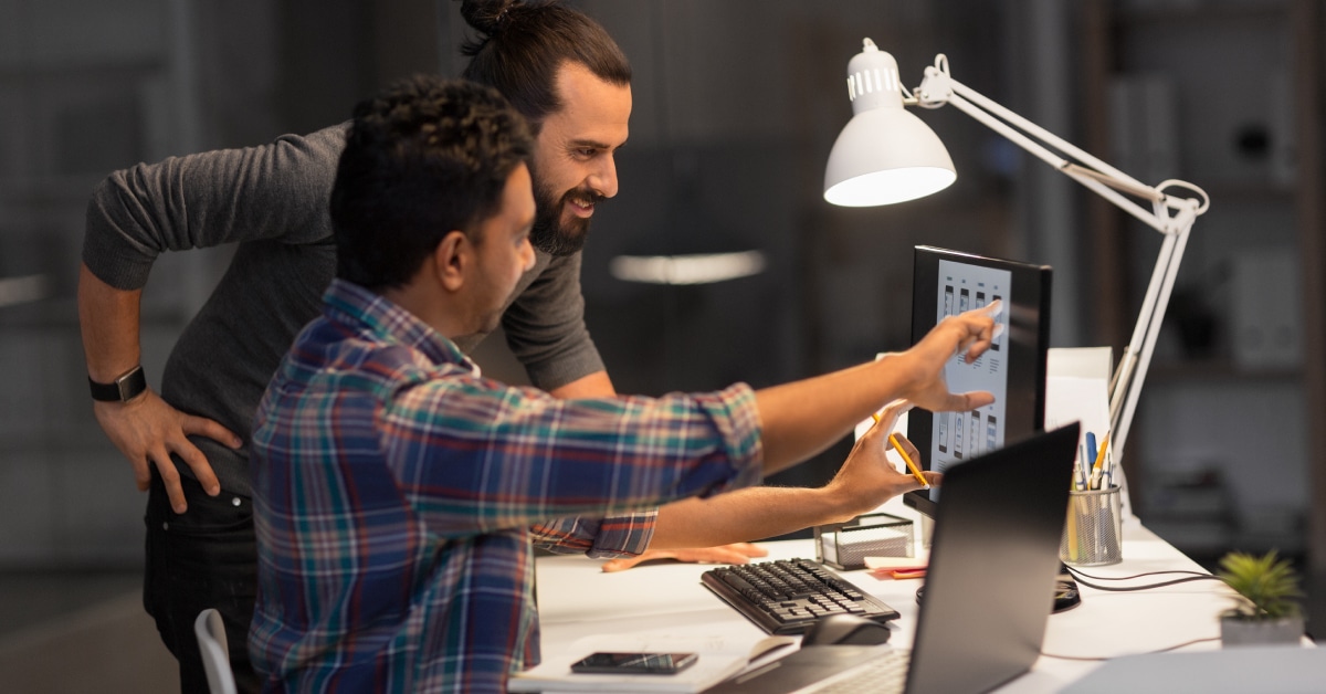 Image of two men looking and pointing at a computer screen.