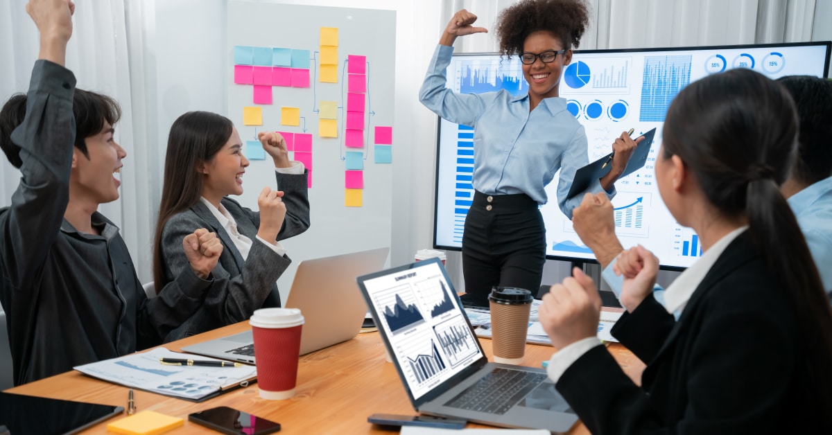 Coworkers gathered around a conference table cheering